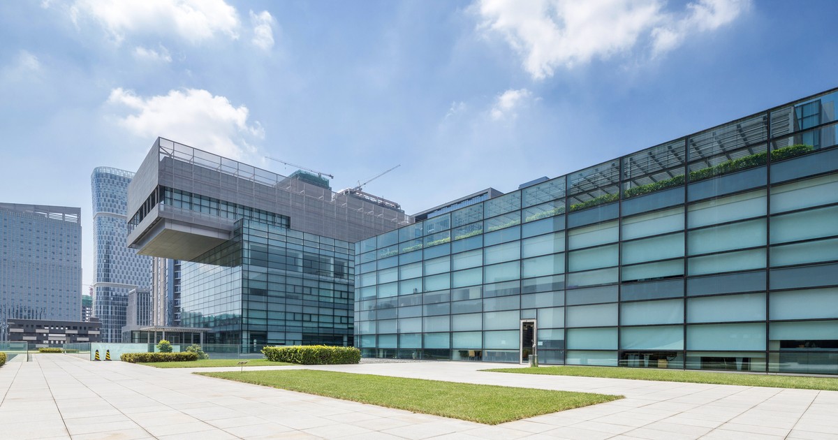 Modern commercial office building exterior with landscaped grounds under a clear sky