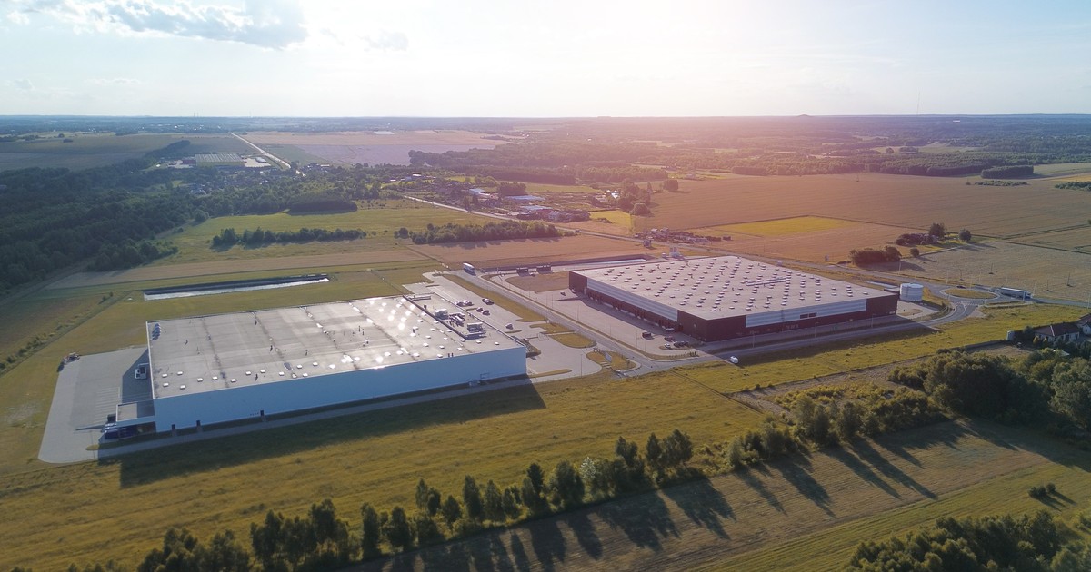 Aerial view of a large warehouse and logistics hub in an industrial area with loading docks and parked trucks