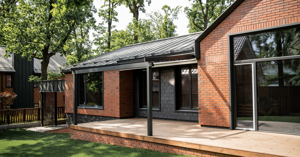 Contemporary brick cottage with large windows beside a green lawn